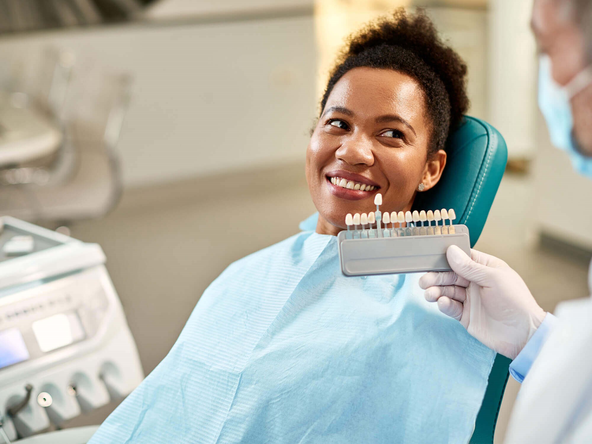 Patient comparing tooth shades with her dentist